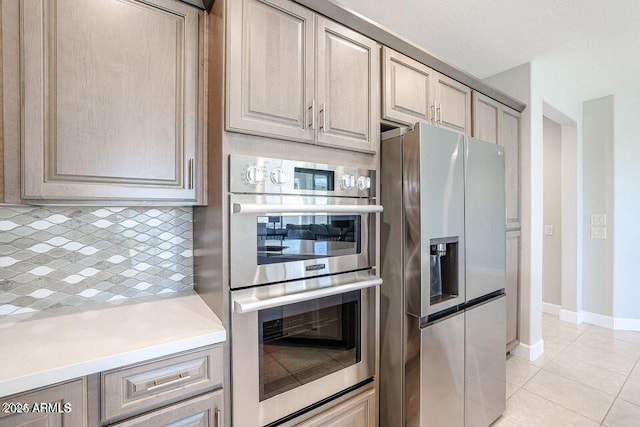 kitchen featuring light tile patterned flooring, appliances with stainless steel finishes, light brown cabinetry, and decorative backsplash