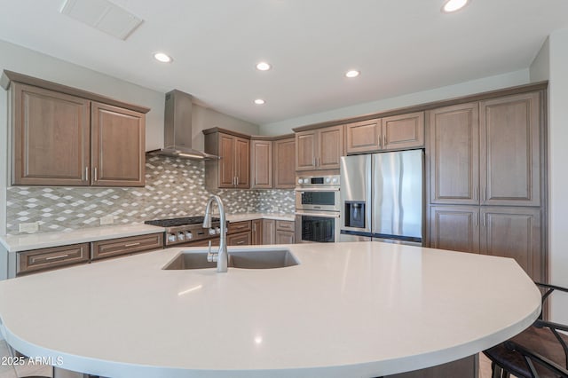 kitchen featuring a large island, wall chimney exhaust hood, and appliances with stainless steel finishes