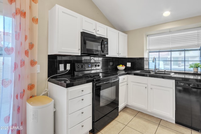 kitchen featuring vaulted ceiling, black appliances, a sink, and white cabinetry