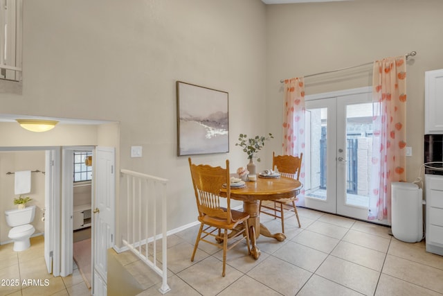 dining room with a high ceiling, light tile patterned flooring, and french doors