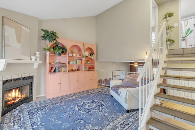 game room featuring a ceiling fan, vaulted ceiling, and a tiled fireplace