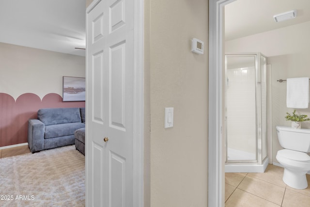 full bath with toilet, a shower stall, and tile patterned floors