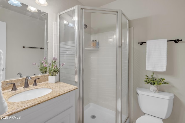 bathroom with a stall shower, vanity, and toilet