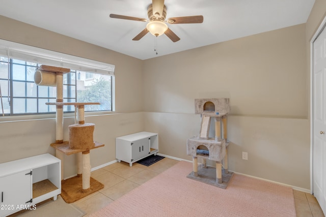 interior space with tile patterned flooring, a ceiling fan, and baseboards