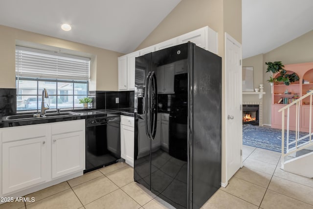 kitchen with dark countertops, black appliances, white cabinetry, and a sink