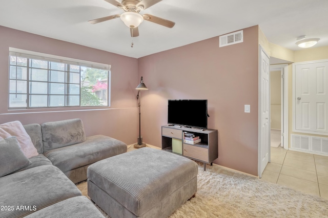 living area featuring light tile patterned floors, ceiling fan, visible vents, and baseboards