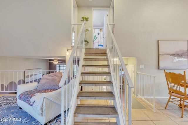 stairway with tile patterned flooring, ceiling fan, and baseboards