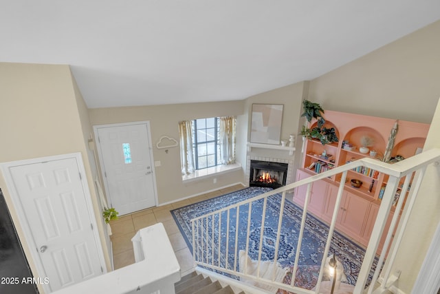 tiled entryway with lofted ceiling, stairs, a fireplace, and baseboards