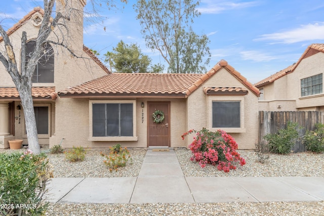 view of front of house with a tile roof, fence, and stucco siding