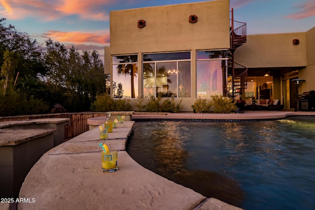 pool at dusk with a patio area