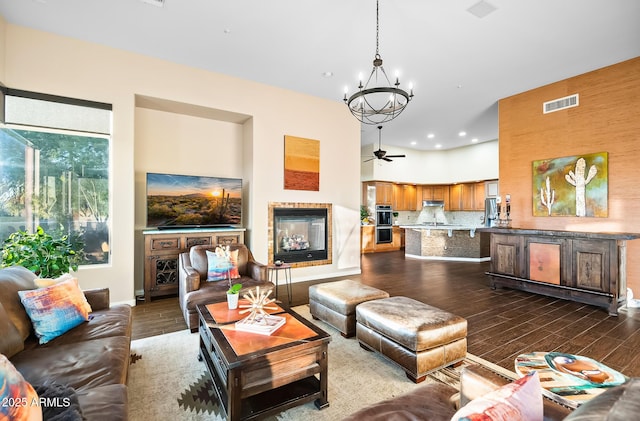 living room featuring dark hardwood / wood-style flooring, a multi sided fireplace, and ceiling fan with notable chandelier