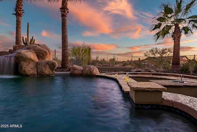 pool at dusk featuring pool water feature