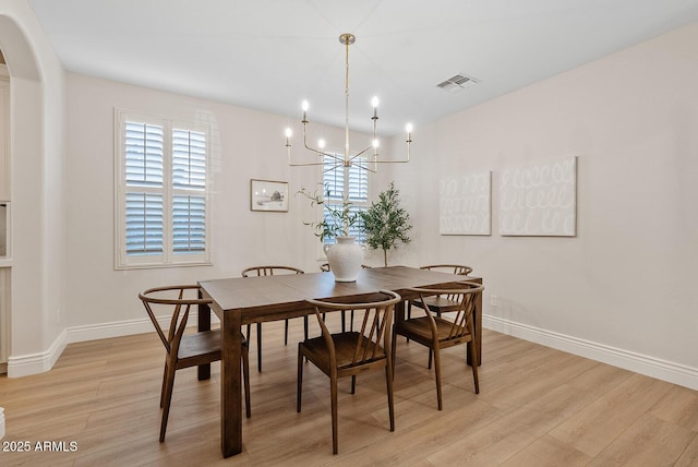 dining room with an inviting chandelier, light wood-type flooring, visible vents, and baseboards