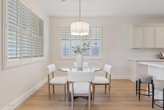 dining space with light wood-style flooring, visible vents, and baseboards