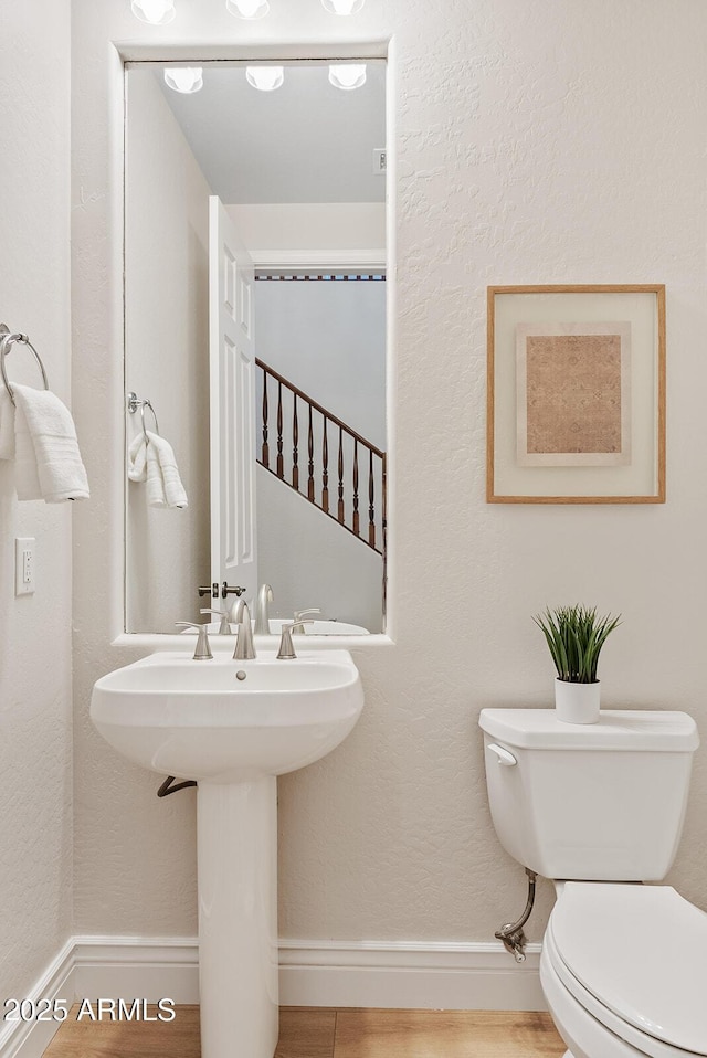 bathroom featuring toilet, baseboards, and wood finished floors