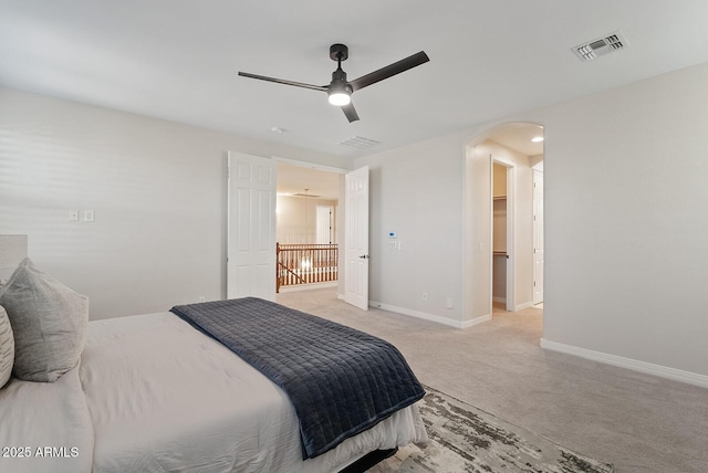 bedroom featuring light carpet, baseboards, visible vents, arched walkways, and a ceiling fan