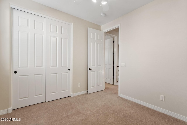 unfurnished bedroom featuring carpet, a closet, ceiling fan, and baseboards