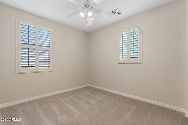 carpeted spare room with ceiling fan, visible vents, and baseboards