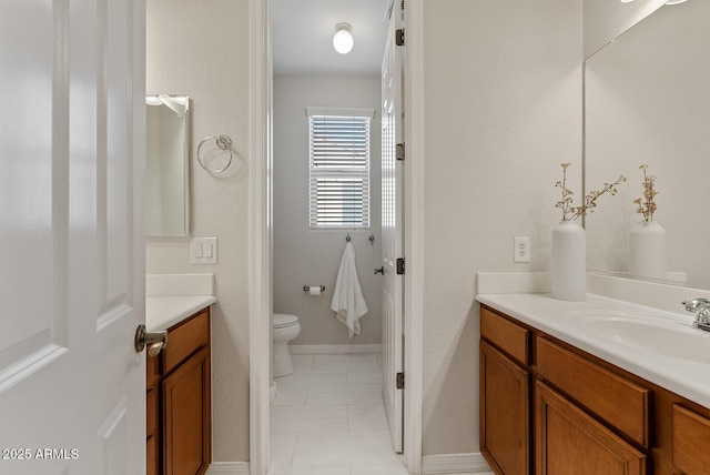 bathroom featuring toilet, tile patterned flooring, vanity, and baseboards