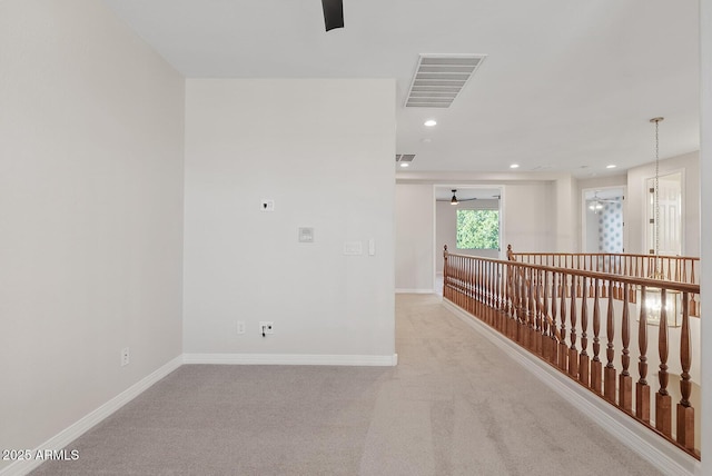 unfurnished room with light carpet, baseboards, visible vents, and a ceiling fan