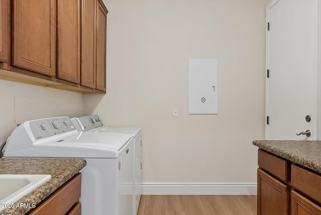 laundry area with light wood finished floors, cabinet space, a sink, separate washer and dryer, and baseboards