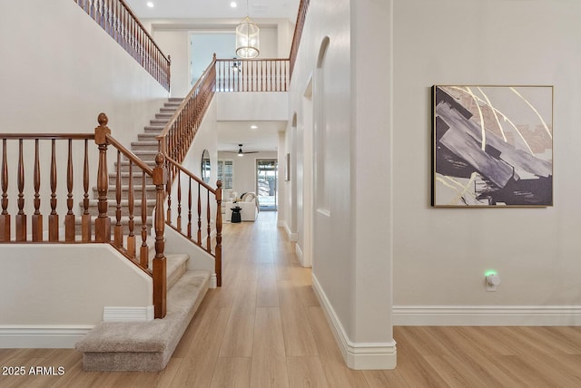 foyer entrance with a high ceiling, stairs, baseboards, and wood finished floors