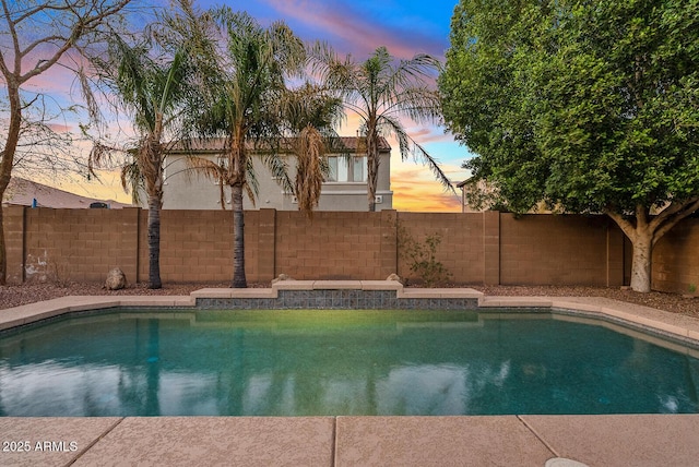 pool at dusk featuring a fenced in pool and a fenced backyard