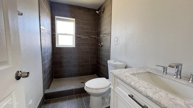 121 E Monte Way, Phoenix, AZ 85042 - bathroom featuring vanity, tiled shower, toilet, wood finished floors, and a textured wall