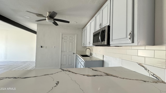 121 E Monte Way, Phoenix, AZ 85042 - kitchen with stainless steel microwave, a sink, light stone countertops, backsplash, and ceiling fan