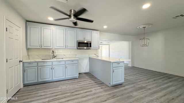 121 E Monte Way, Phoenix, AZ 85042 - kitchen featuring stainless steel microwave, a sink, decorative backsplash, light wood finished floors, and a ceiling fan