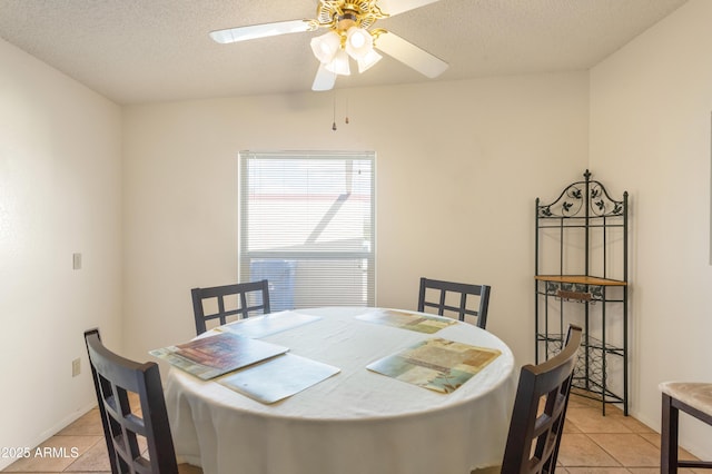 dining space with light tile patterned flooring, ceiling fan, a textured ceiling, and baseboards