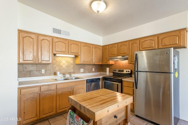 kitchen with lofted ceiling, under cabinet range hood, stainless steel appliances, a sink, and visible vents