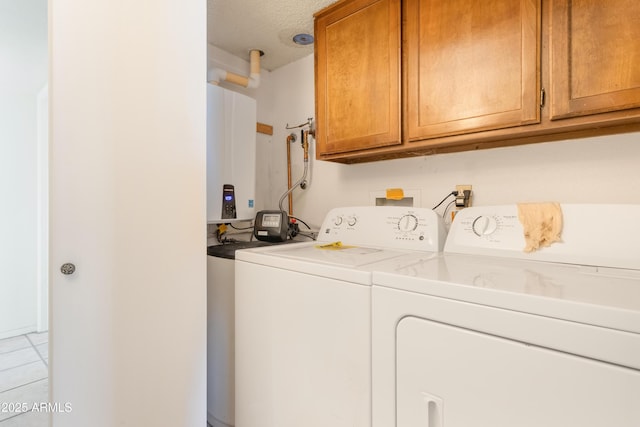 laundry area featuring tankless water heater, cabinet space, washing machine and clothes dryer, and light tile patterned flooring