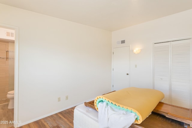 bedroom with a closet, visible vents, ensuite bathroom, light wood-type flooring, and baseboards