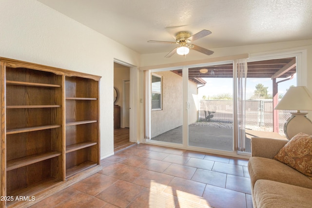 living room featuring a ceiling fan, tile patterned flooring, and a textured ceiling