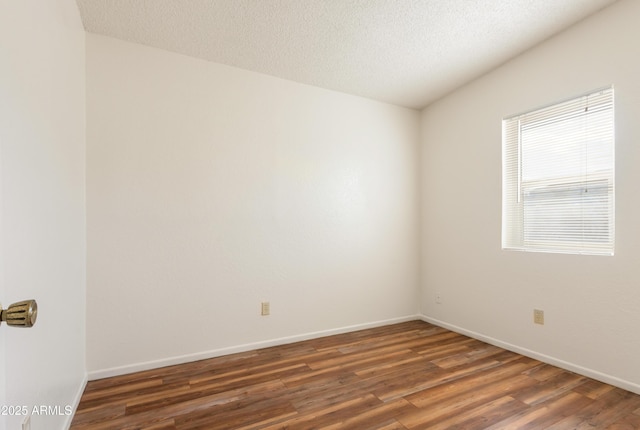 spare room with a textured ceiling, baseboards, and wood finished floors