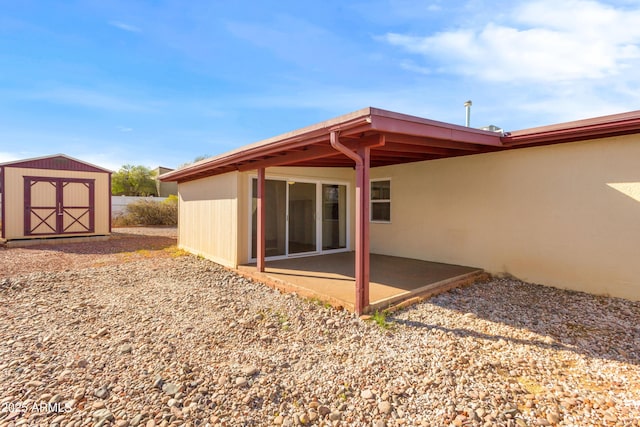 back of property with an outbuilding, a shed, and a patio area