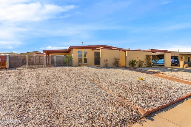 view of front of property featuring an attached carport, a gate, fence, and stucco siding