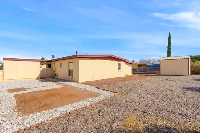 rear view of house featuring a patio, fence, an outdoor structure, a shed, and stucco siding