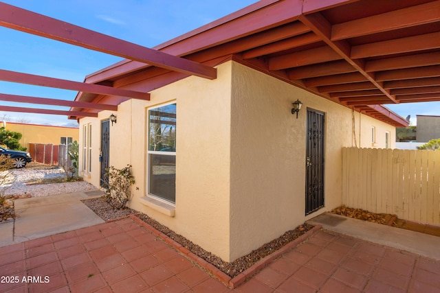 view of side of home featuring stucco siding, a patio, and fence