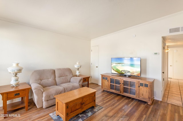 living room with baseboards, visible vents, wood finished floors, and ornamental molding