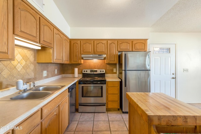 kitchen featuring under cabinet range hood, backsplash, stainless steel appliances, and a sink