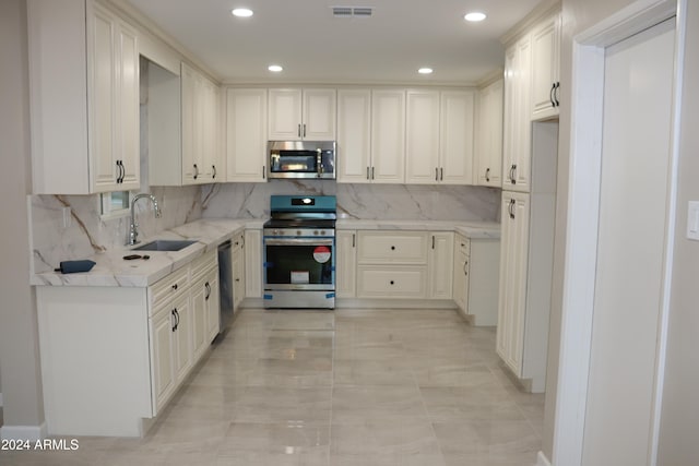 kitchen with white cabinets, stainless steel appliances, sink, and tasteful backsplash