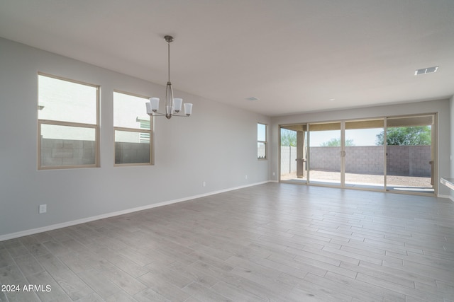 spare room with a notable chandelier and light hardwood / wood-style floors