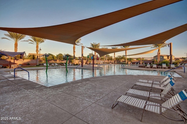 pool at dusk featuring a patio