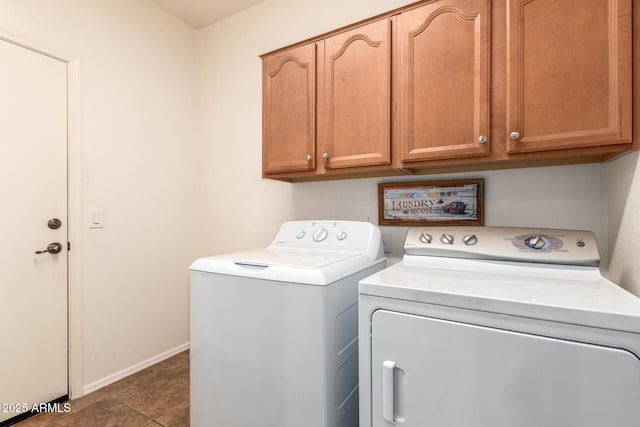 clothes washing area with cabinets, washer and dryer, and dark tile patterned floors