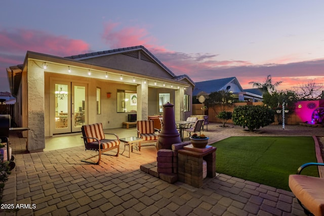 back house at dusk with a lawn and a patio area