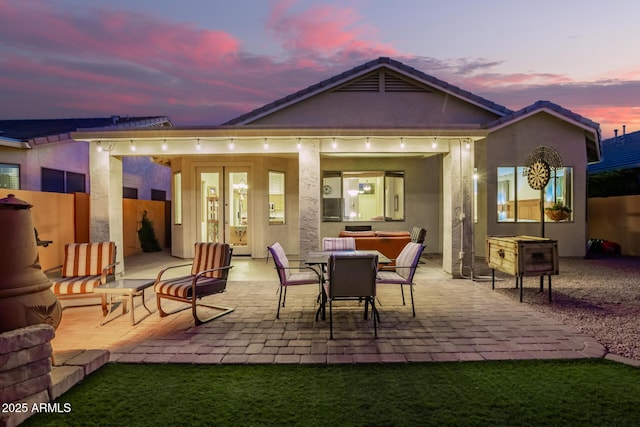 back house at dusk featuring a hot tub and a patio