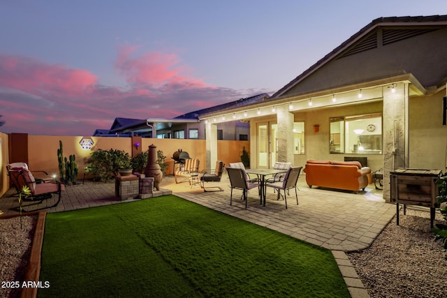 back house at dusk with a yard and a patio area