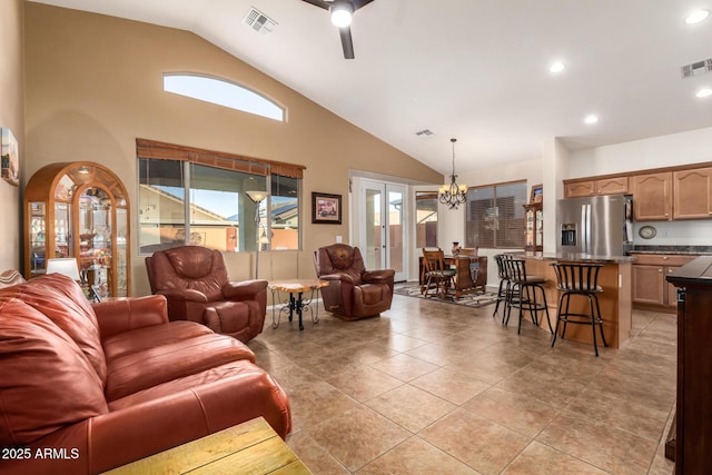 living room with ceiling fan with notable chandelier, high vaulted ceiling, and light tile patterned floors